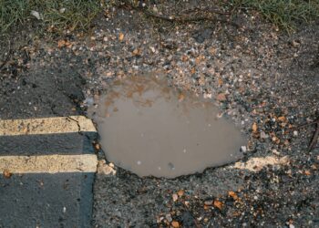 Buraco na estrada com água, risco para condutores, sinalização de buracos em Portugal.