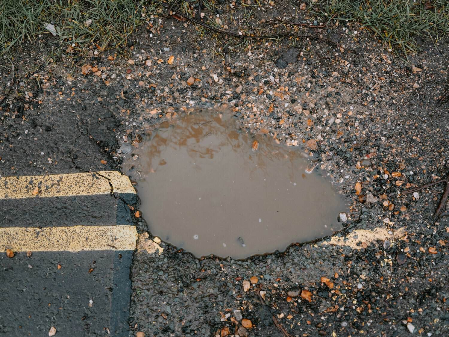 Buraco na estrada com água, risco para condutores, sinalização de buracos em Portugal.