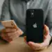 IPhone recondicionado preto com dinheiro na mão, destacando economia em tecnologia Apple.