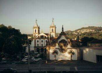 Árvore e igreja histórica em Famalicão, Portugal, com vista para o céu ao entardecer.