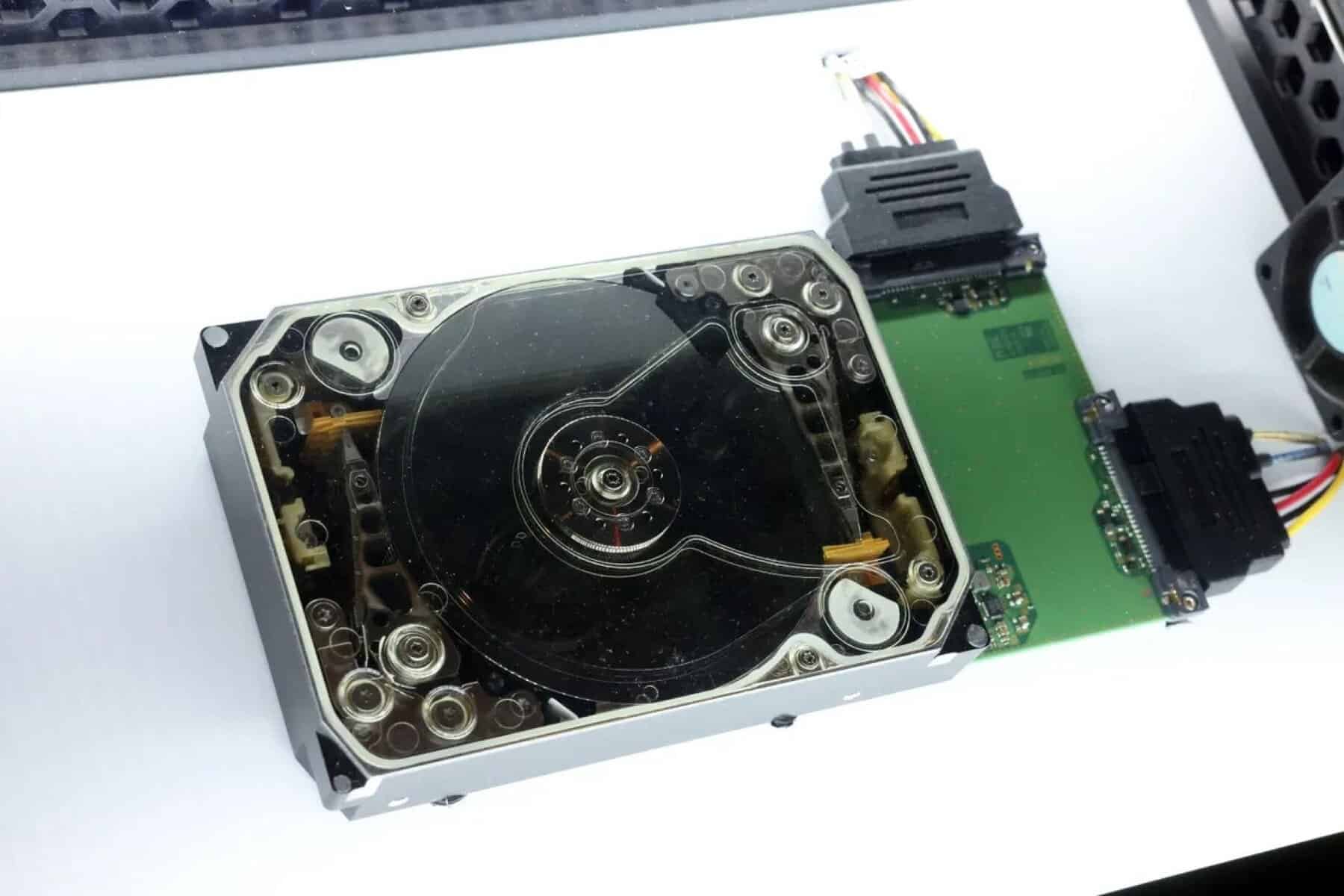 Disco SSD SATA aberto, mostrando componentes internos e conexão com placa de circuito.
